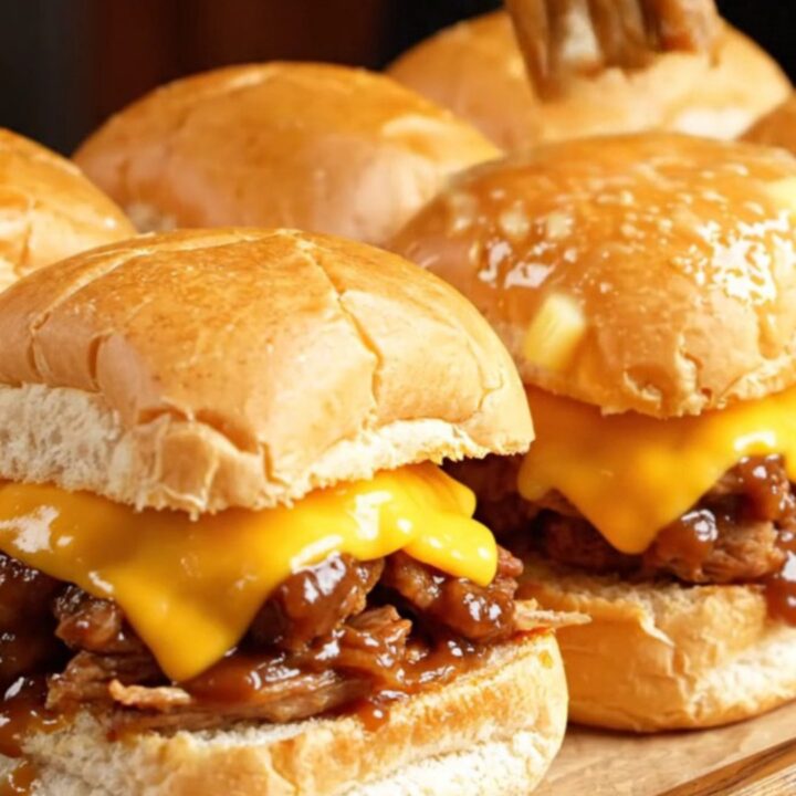 A close-up shot of Dr. Pepper and chipotle BBQ pulled pork sliders on Hawaiian rolls with melted cheese.