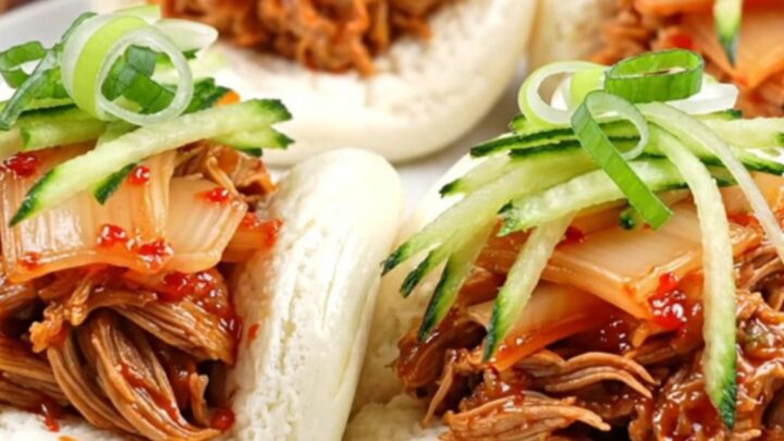Glossy Korean gochujang pulled pork in a slow cooker with sesame seeds.