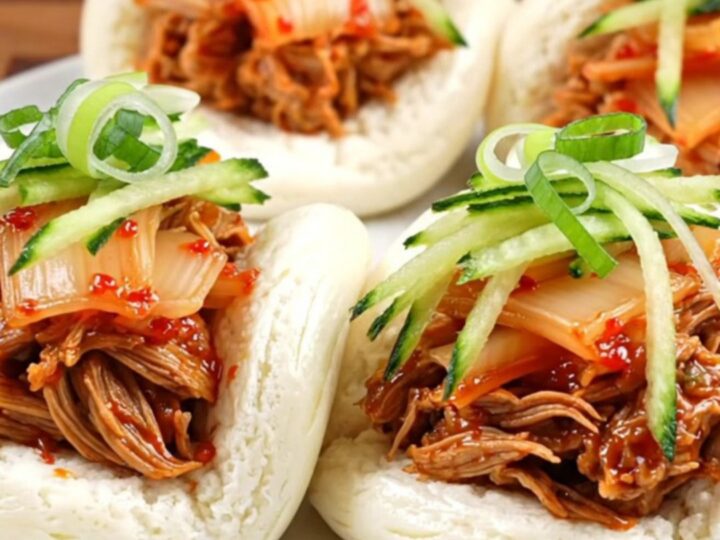 Glossy Korean gochujang pulled pork in a slow cooker with sesame seeds.