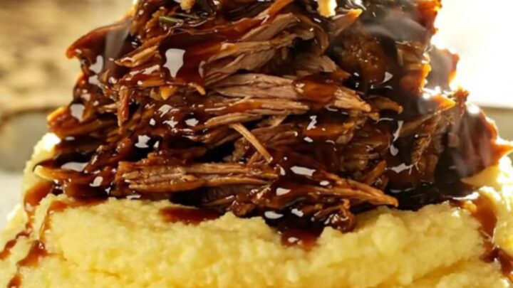 A close-up of a slow cooker filled with shredded balsamic fig pulled pork, displaying a rich