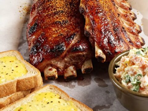 Close-up of succulent Memphis-style ribs on butcher paper with a glossy, caramelized dry-rub crust.