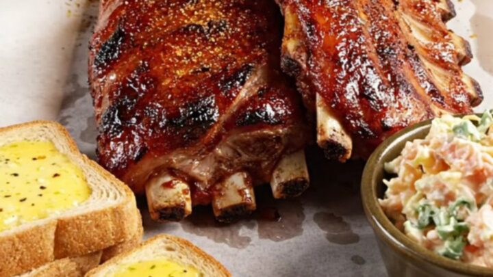 Close-up of succulent Memphis-style ribs on butcher paper with a glossy, caramelized dry-rub crust.