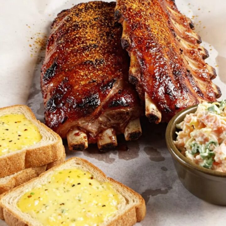 Close-up of succulent Memphis-style ribs on butcher paper with a glossy, caramelized dry-rub crust.