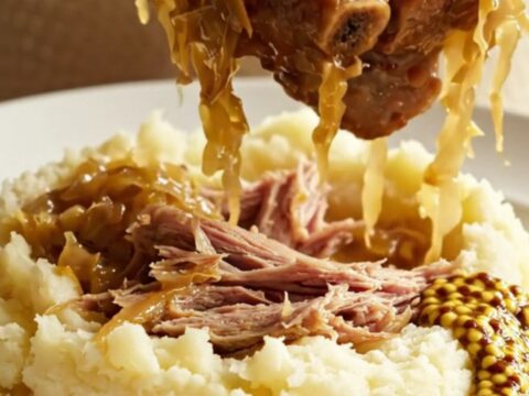 A rustic crockpot filled with tender pork ribs, sliced kielbasa, and golden sauerkraut, steaming and ready to serve.