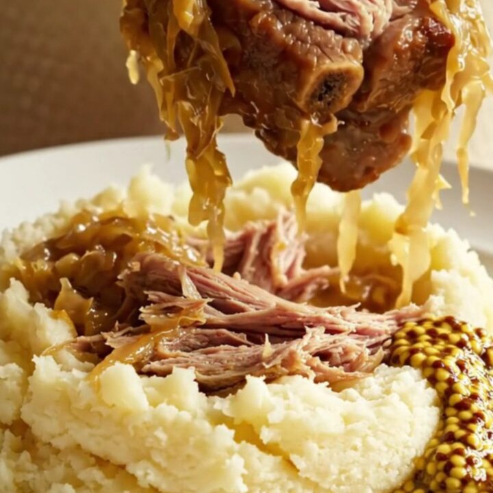 A rustic crockpot filled with tender pork ribs, sliced kielbasa, and golden sauerkraut, steaming and ready to serve.