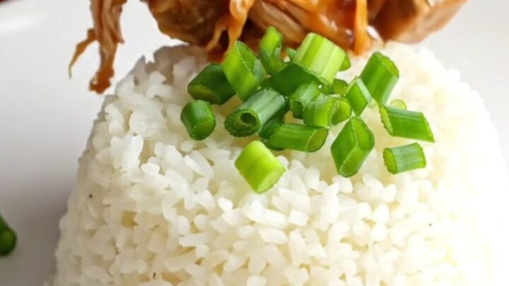 A vibrant bowl of sweet and sour pork chops with pineapple and bell peppers over white rice.