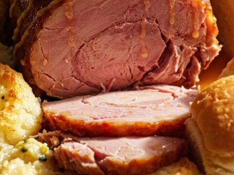 A festive holiday ham with a golden honey-mustard glaze served on a platter with scalloped potatoes.