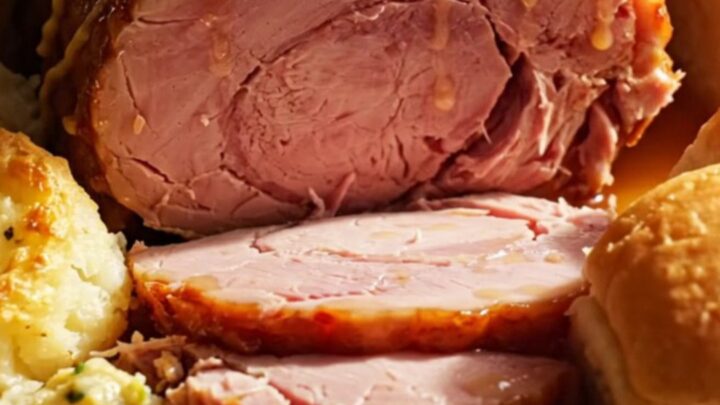 A festive holiday ham with a golden honey-mustard glaze served on a platter with scalloped potatoes.