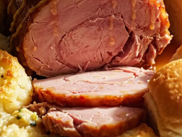A festive holiday ham with a golden honey-mustard glaze served on a platter with scalloped potatoes.