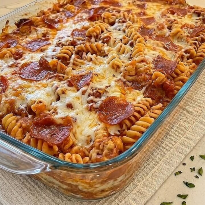 A glass baking dish filled with cheesy pizza pasta bake, featuring melted mozzarella and crispy pepperoni.
