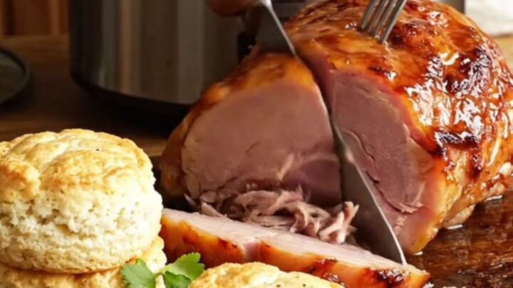 A glistening, diamond-scored picnic ham with a rich apricot-Dijon glaze on a wooden board.
