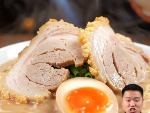 A close-up of a tender, sliced Chashu pork belly log resting in a dark, glossy soy-mirin glaze.
