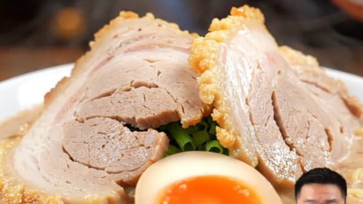 A close-up of a tender, sliced Chashu pork belly log resting in a dark, glossy soy-mirin glaze.