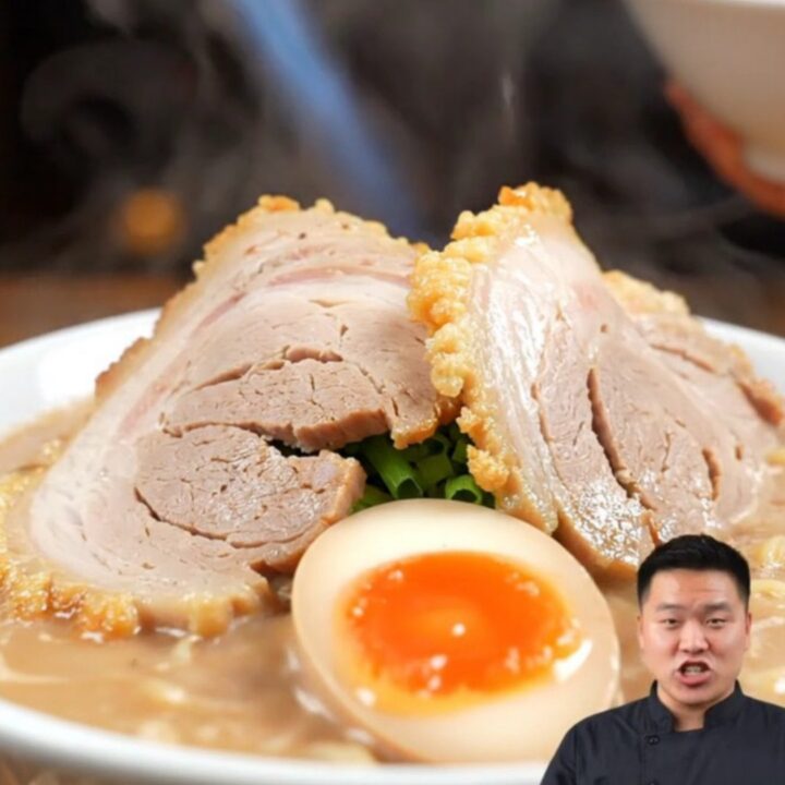 A close-up of a tender, sliced Chashu pork belly log resting in a dark, glossy soy-mirin glaze.