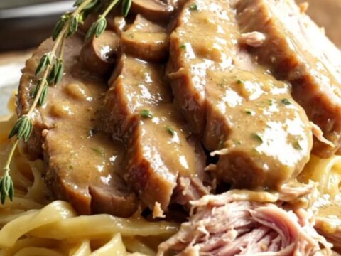 A rustic stoneware slow cooker filled with creamy mushroom gravy and tender sliced pork loin.