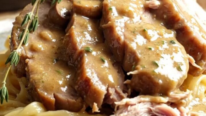 A rustic stoneware slow cooker filled with creamy mushroom gravy and tender sliced pork loin.