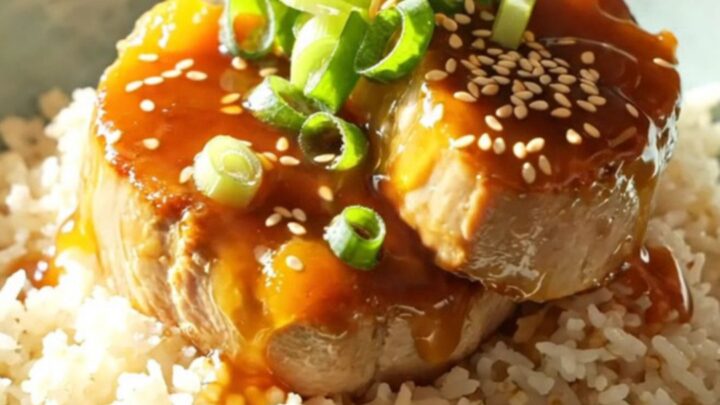 A white ceramic slow cooker filled with sliced, golden-glazed pork tenderloin medallions.