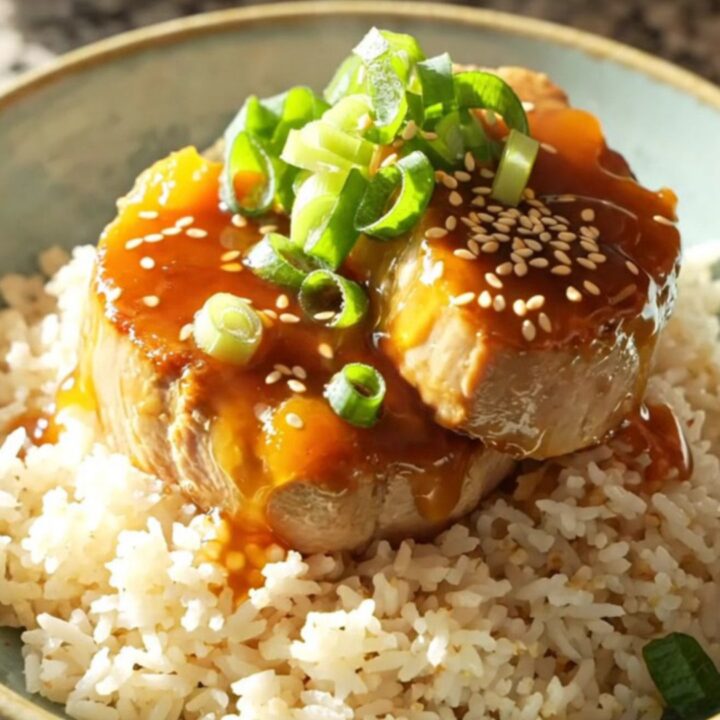 A white ceramic slow cooker filled with sliced, golden-glazed pork tenderloin medallions.