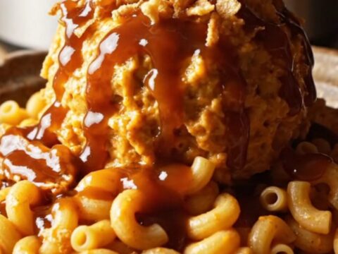 A close-up of a slow cooker filled with creamy BBQ pulled pork mac and cheese garnished with crispy onions.