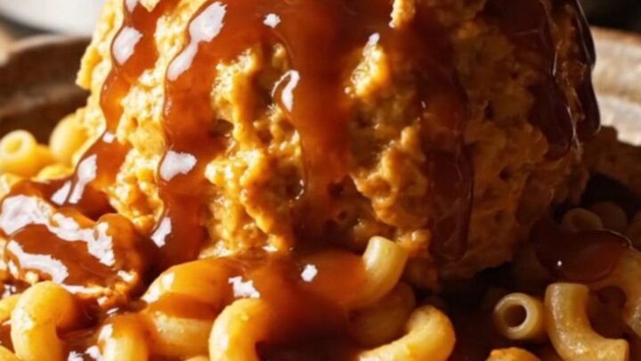 A close-up of a slow cooker filled with creamy BBQ pulled pork mac and cheese garnished with crispy onions.