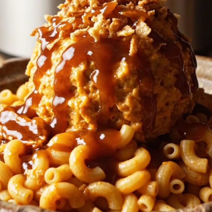A close-up of a slow cooker filled with creamy BBQ pulled pork mac and cheese garnished with crispy onions.