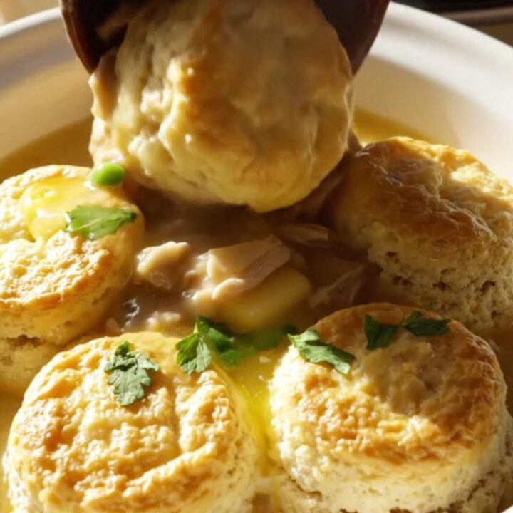 A close-up of a vintage cream crockpot filled with creamy chicken stew, tender vegetables, and fluffy biscuit dumplings.