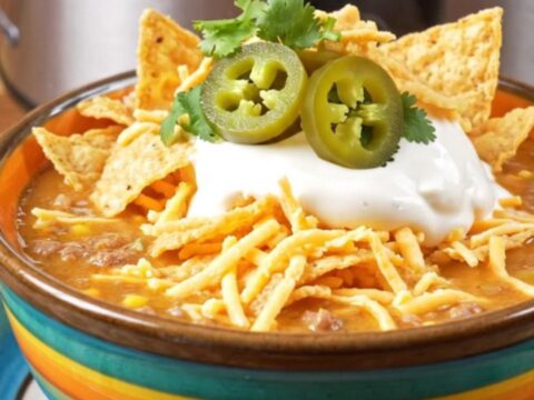 A bowl of creamy taco ranch beef soup topped with sour cream, cilantro, and crushed tortilla chips.