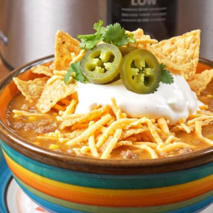 A bowl of creamy taco ranch beef soup topped with sour cream, cilantro, and crushed tortilla chips.