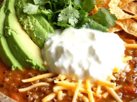 A warm stoneware bowl filled with smoky sweet potato and black bean chili topped with avocado and cilantro.