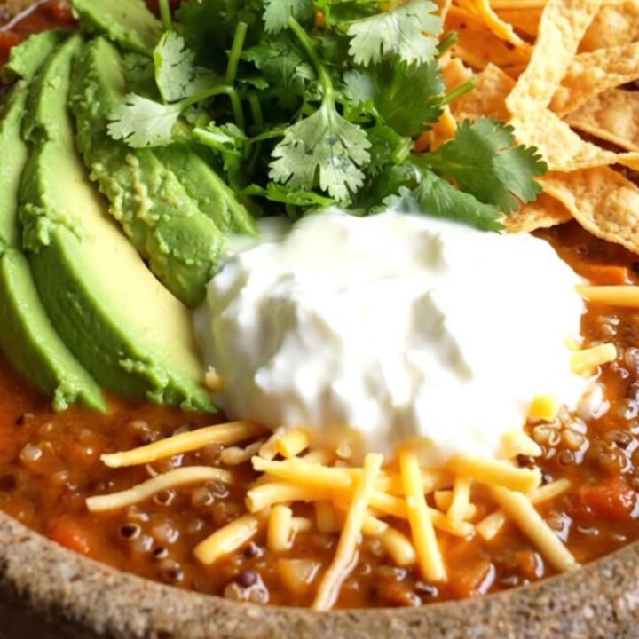A warm stoneware bowl filled with smoky sweet potato and black bean chili topped with avocado and cilantro.