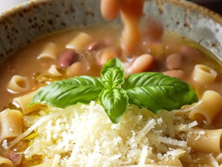 A warm bowl of creamy Italian sausage pasta fagioli topped with fresh basil and Parmesan cheese.