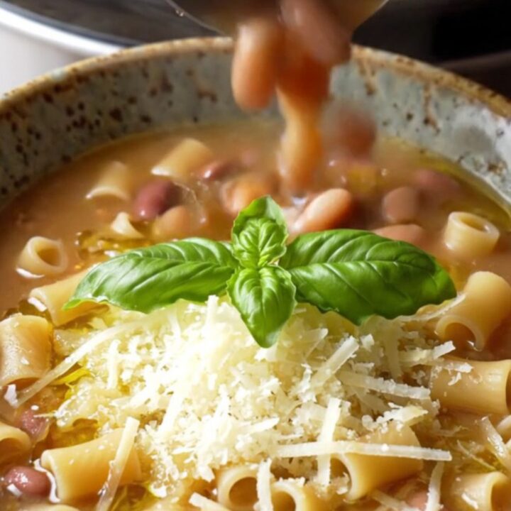 A warm bowl of creamy Italian sausage pasta fagioli topped with fresh basil and Parmesan cheese.