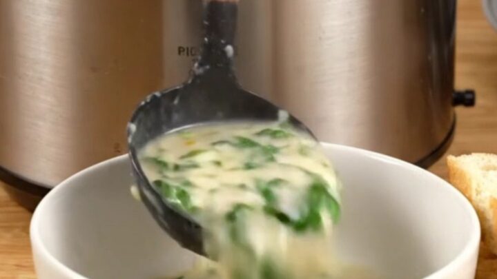 Creamy spinach artichoke chicken served in a ceramic bowl with toasted baguette slices on the side.