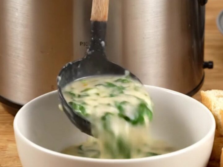 Creamy spinach artichoke chicken served in a ceramic bowl with toasted baguette slices on the side.