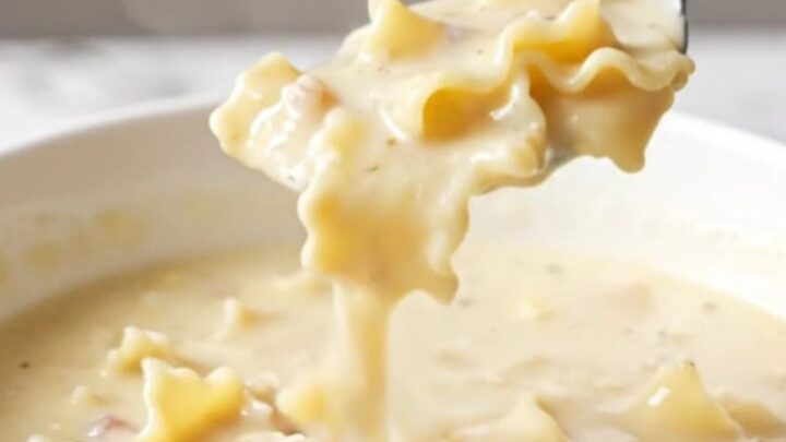 A bowl of creamy white lasagna soup with sausage, noodles, and spinach.