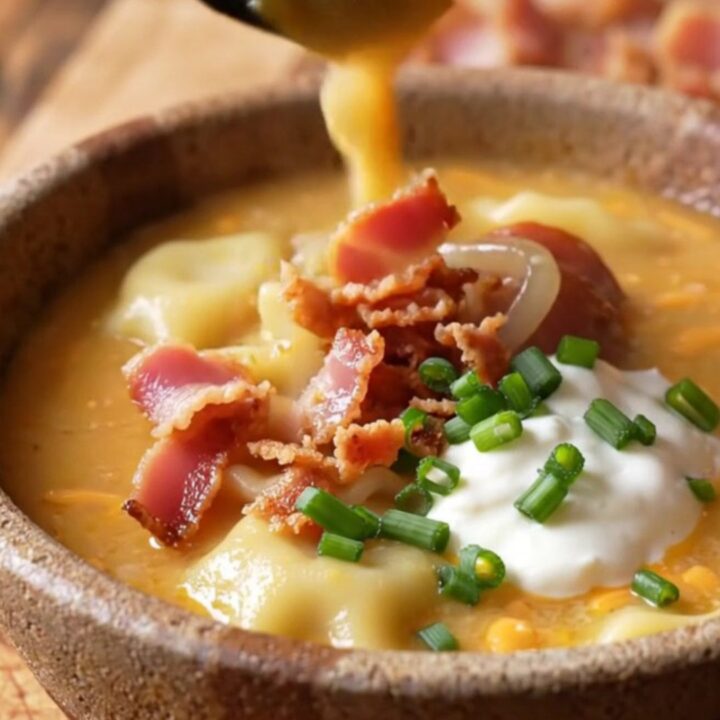 A rustic bowl of creamy pierogi soup topped with crispy bacon, caramelized onions, and fresh chives