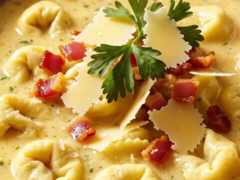 A warm, creamy chicken Alfredo tortellini soup in a ceramic bowl with crispy pancetta and fresh parsley.