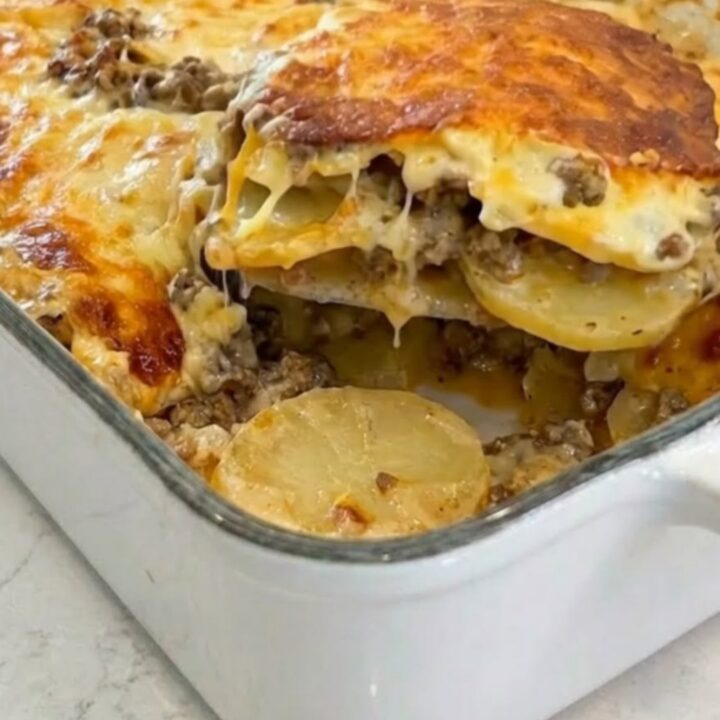 A close-up shot of a bubbling, golden-brown cheesy potato and ground beef casserole in a white baking dish.