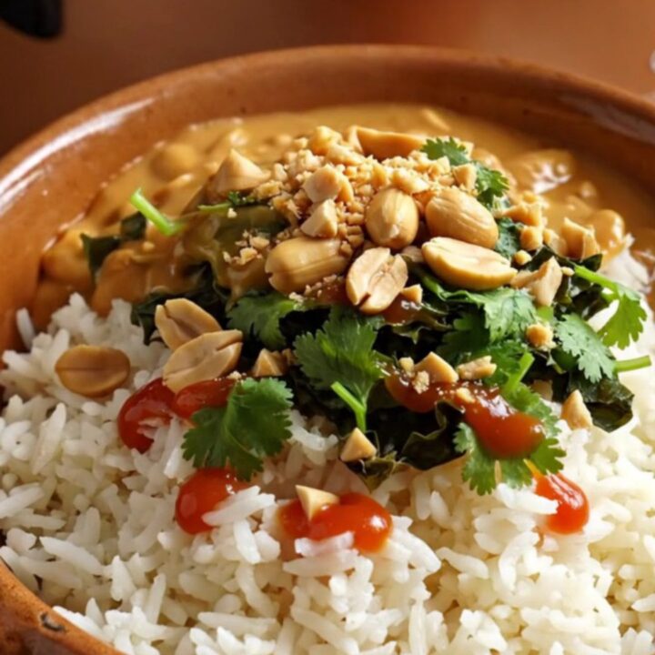 A close-up of a bronze ceramic slow cooker filled with creamy peanut and sweet potato chicken stew.