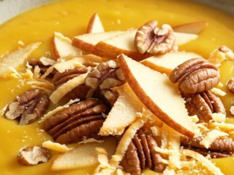 A warm ceramic bowl filled with creamy golden honeynut squash soup