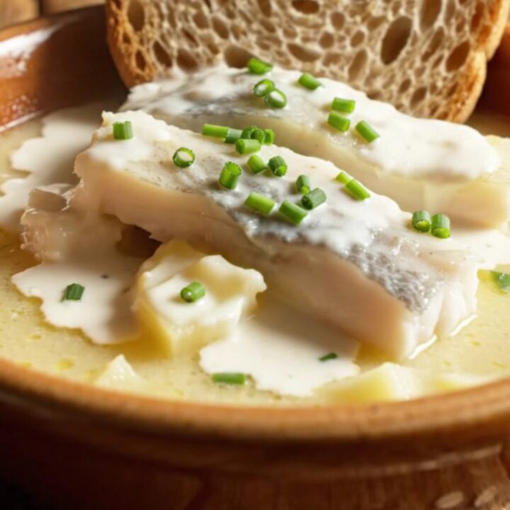 A warm stoneware bowl filled with creamy, ivory-gold smoked haddock chowder, topped with chives and served with crusty bread.