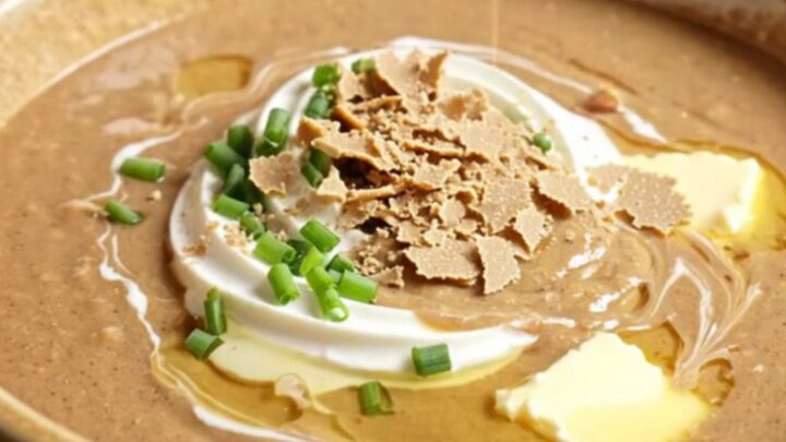 A warm, velvety chestnut and porcini bisque in a porcelain bowl, garnished with crème fraîche and crispy sage.
