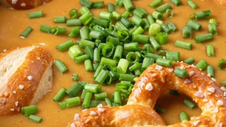 A warm, bubbling pot of creamy beer cheese dip served in a rustic crockpot with soft pretzel bites.