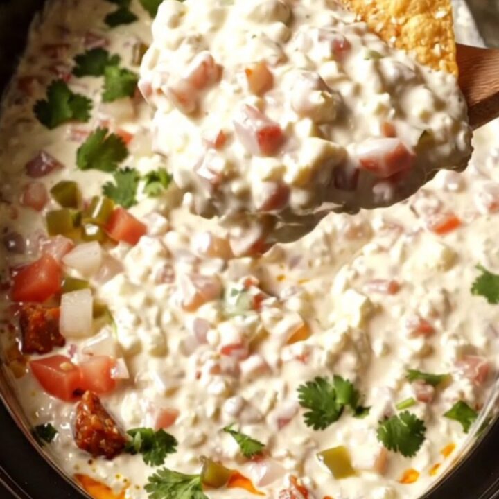A creamy white chorizo queso dip in a black ceramic slow cooker, garnished with fresh cilantro and pico de gallo.