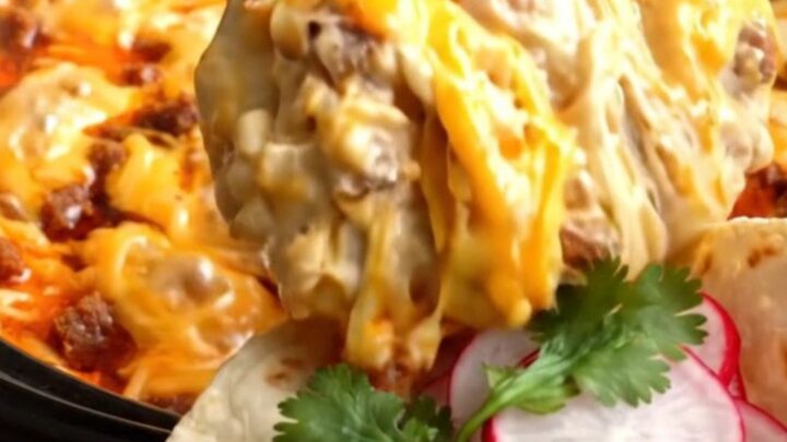 A close-up shot of a molten cheese pull from a dark ceramic Crockpot filled with chorizo and poblano fundido.