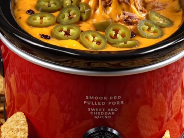A close-up of a waffle-cut chip scooping up creamy BBQ pulled pork queso dip with a cheese pull.