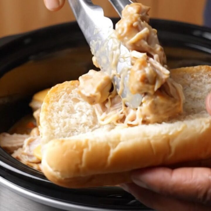 A close-up of creamy Philly cheesesteak chicken in a toasted hoagie roll with melted provolone cheese.