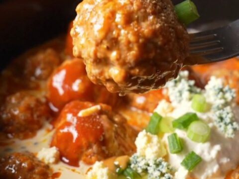 A close-up of buffalo ranch chicken meatballs in a ceramic slow cooker