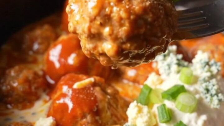 A close-up of buffalo ranch chicken meatballs in a ceramic slow cooker
