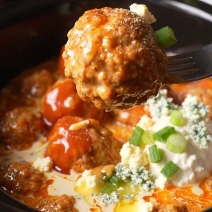 A close-up of buffalo ranch chicken meatballs in a ceramic slow cooker